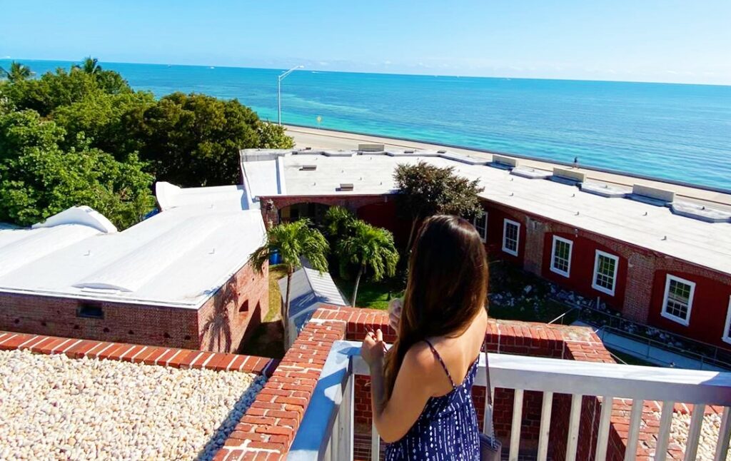 woman stands on patio by ocean explaining the work and travel program in key west