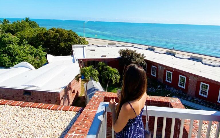 woman stands on patio by ocean explaining the work and travel program in key west